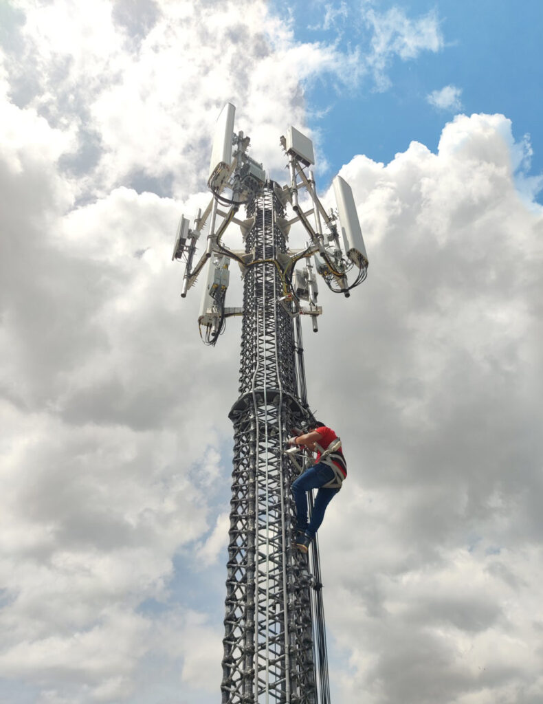 A man climbing up the side of a cell phone tower.