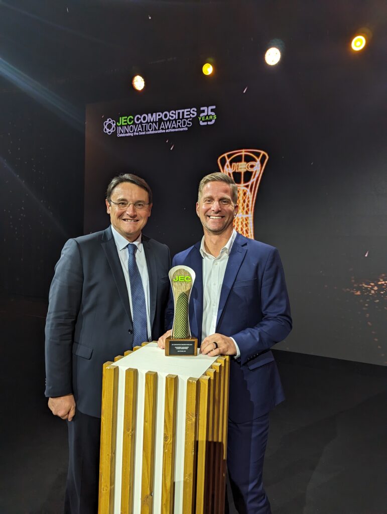 Two men standing next to a trophy on top of a table.