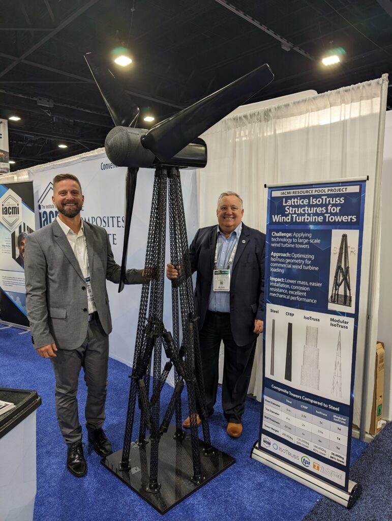 Two men standing next to a large wind turbine.