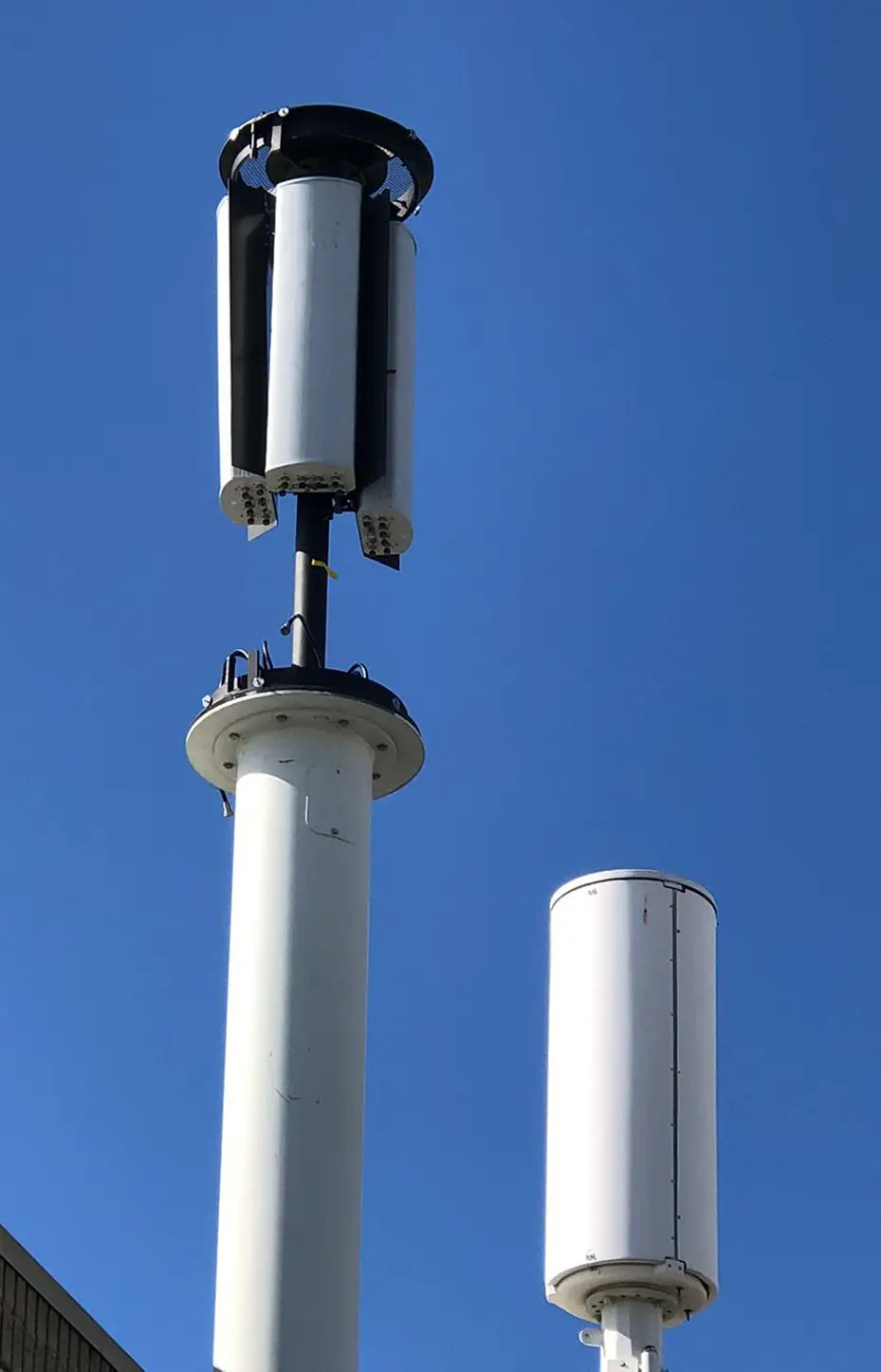 A white pole with two antennas on top of it.